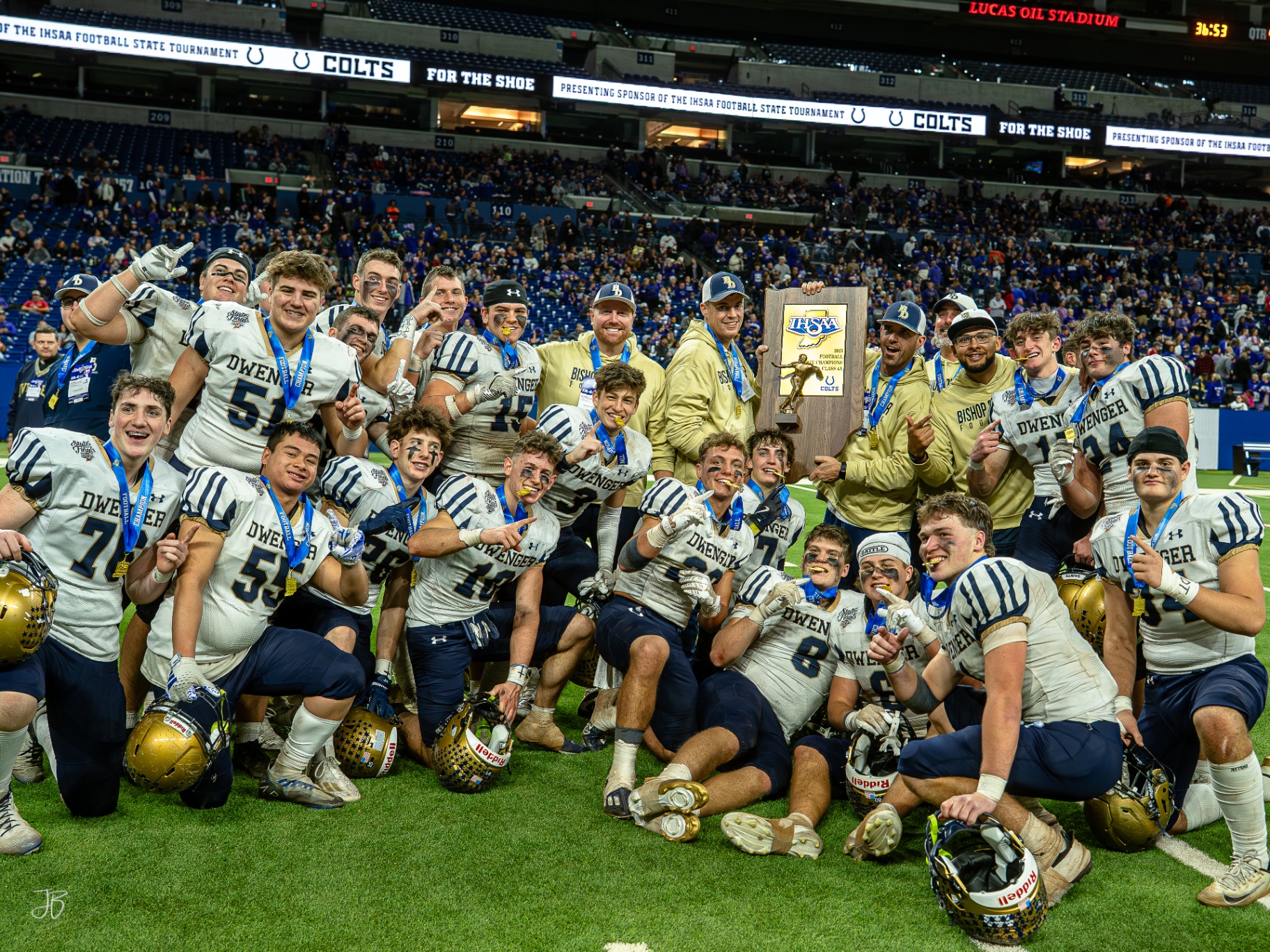 Coach Knepper celebrating with Bishop Dwenger players and trophy