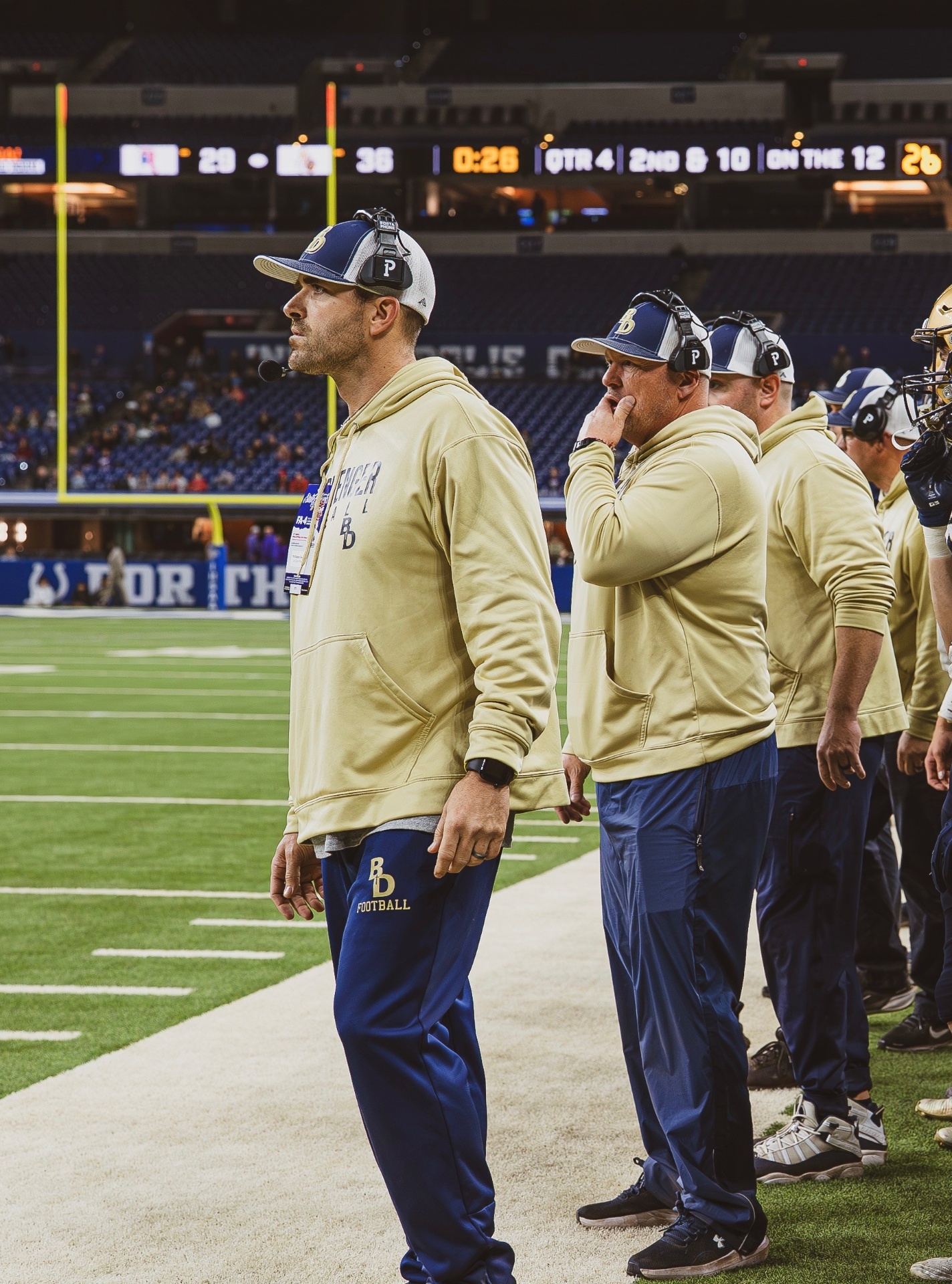 Bishop Dwenger defensive coaches on the sideline at Lucas Oil Stadium during the 2025 State Championship